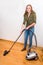 Young woman cleans floor with vacuum cleaner