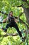 Young woman climbing in adventure rope park