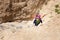 Young woman climbing desert canyon cliff.