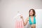 Young woman with clothes on hanger behind folding screen against light background, space for text.