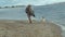 Young woman in a coat with a girl with curly hair, mom and daughter, run, play with a brown dog on the beach, brood her