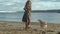 Young woman in a coat with a girl with curly hair, mom and daughter, run, play with a brown dog on the beach, brood her