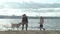 Young woman in a coat with a girl with curly hair, mom and daughter, run, play with a brown dog on the beach, brood her