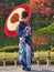 A young woman in colourful national dress poses for photographs in a public park in Kanazawa, Japan