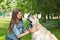 Young woman combing fur golden retriever dog on a green lawn