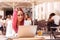 Young woman concentrated using a laptop at a table outside a cafe