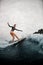 Young woman confidently stands on the wake surf board and rides the wave.