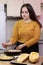 Young woman cooking in a kitchen. Housewife preparing vegetables for cooking. Girl put fresh fried meat into yellow zucchini.