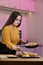 Young woman cooking in a kitchen. Housewife preparing vegetables for cooking. Girl put fresh fried meat into yellow zucchini.