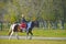 A young woman in a Cossack uniform, riding a horse, keeps order in the park. Russia