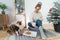 Young Woman in cosy sweater with cat pet, drinking hot tea, relaxing on floor cushions near potted christmas tree in