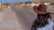 Young woman with a cowboy hat walking through a lonesome street in Dolan Springs Arizona