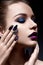 Young woman with creative make-up and violet lips with a gradient and sparkles on the face. Beautiful model with bright nails with