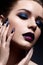 Young woman with creative make-up and violet lips with a gradient and sparkles on the face. Beautiful model with bright nails with