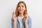 Young woman with crossed fingers and wishing all the best, over white background