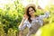 Young woman among cultivated grape plants in greenhouse