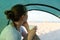 Young woman with cup in hands sits in tent and looks at beach and sea. Camping. adventure lifestyle