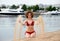 Young woman with curling hair sit on a beach and plays with sand