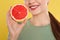 Young woman with cut grapefruit on background, closeup. Vitamin rich food