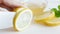 Young woman cutting lemon with knife on white wooden desk