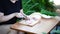 Young woman cutting sausage on wooden board outdoors. Women\'s hands cutting sausage goods with knife on chopping board.