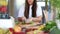 Young woman cutting spinach on wooden board