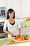 Young woman cutting vegetables in kitchen