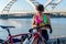 Young woman cyclist eating an energy bar and having a rest by the river bank.