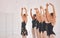 Young woman dance instructor teaching a ballet class to a group of a children in her studio. Ballerina teacher working