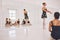 Young woman dance instructor teaching a ballet class to a group of a children in her studio. Ballerina teacher working