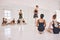 Young woman dance instructor teaching a ballet class to a group of a children in her studio. Ballerina teacher working