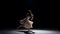 Young woman dancer dancing contemporary dance, jumping and doing a split, on black, shadow