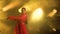 A young woman dancer in a red sari. Indian folk dance. Shot in a dark studio with smoke and yellow neon lighting.