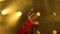 A young woman dancer in a red sari. Indian folk dance. Shot in a dark studio with smoke and yellow neon lighting.