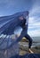 Young woman dancer tossing blue fabric on a Connecticut beach.