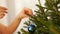 A young woman decorates a Christmas tree with blue balls.