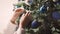 Young woman decorates Christmas tree on New Year\\\'s Eve at home