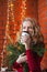 A young woman decorates a house for Christmas and New Year. Drinks cofee. Against the background of a brick wall