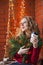 A young woman decorates a house for Christmas and New Year. Drinks cofee. Against the background of a brick wall