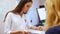 Young woman dentist leafing through the patient`s medical book. The patient is sitting in front of the doctor.