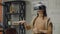 Young woman designer in office in virtual reality helmet with hands makes movements imitating the work of graphic