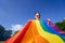 A young woman develops a rainbow flag against the sky