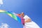 A young woman develops a rainbow flag against the sky