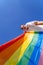 A young woman develops a rainbow flag against the sky