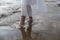A young woman dips her bare feet into the gentle surf of the incoming tide.