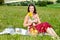 Young woman in dirndl sitting in meadow and holding sunflower