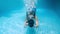 Young woman dives into the water. View from under the water, spray. Summer holiday concept, jump to the pool, Girl