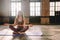 Young woman do complex of stretching yoga asanas in loft style class. Female meditate in lotus position with closed eyes