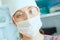 Young woman doctor anesthesiologist dressed in mask, glasses and hat ready for surgery and looking into the camera