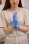 Young woman doctor or cosmetologist putting blue latex protective medical gloves  in beauty clinic